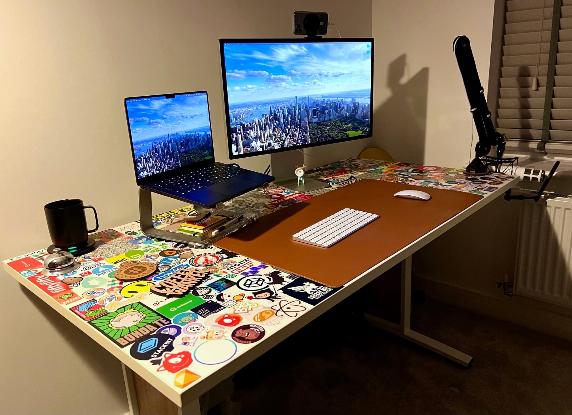 Desk setup with computer, monitor, microphone, keyboard and mouse. Other items include an Ember mug and Dotgridco desk mat